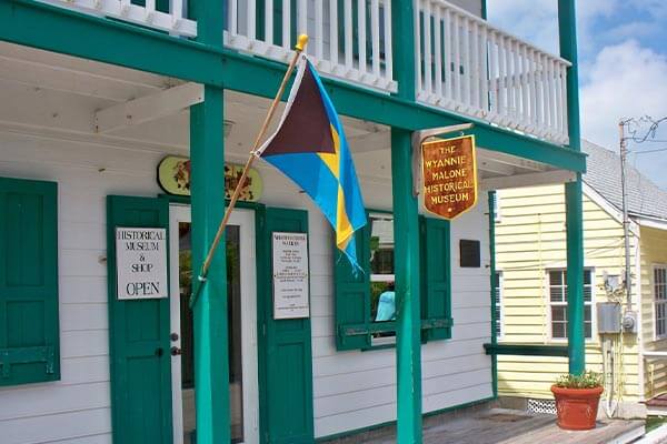 A blue and green building with a flag on the front porch, offering daily freight services to the Bahamas.