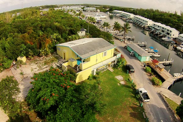 An aerial view of a yellow house near a dock, highlighting its proximity to the dock.